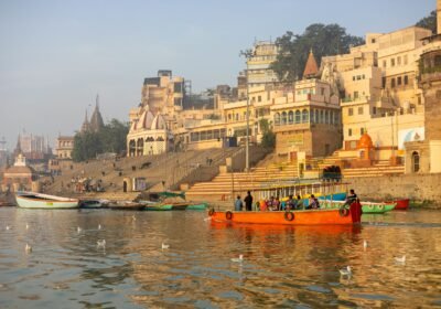 Colourful wooden boats moored along the ghats of Varanasi with the old city skyline behind