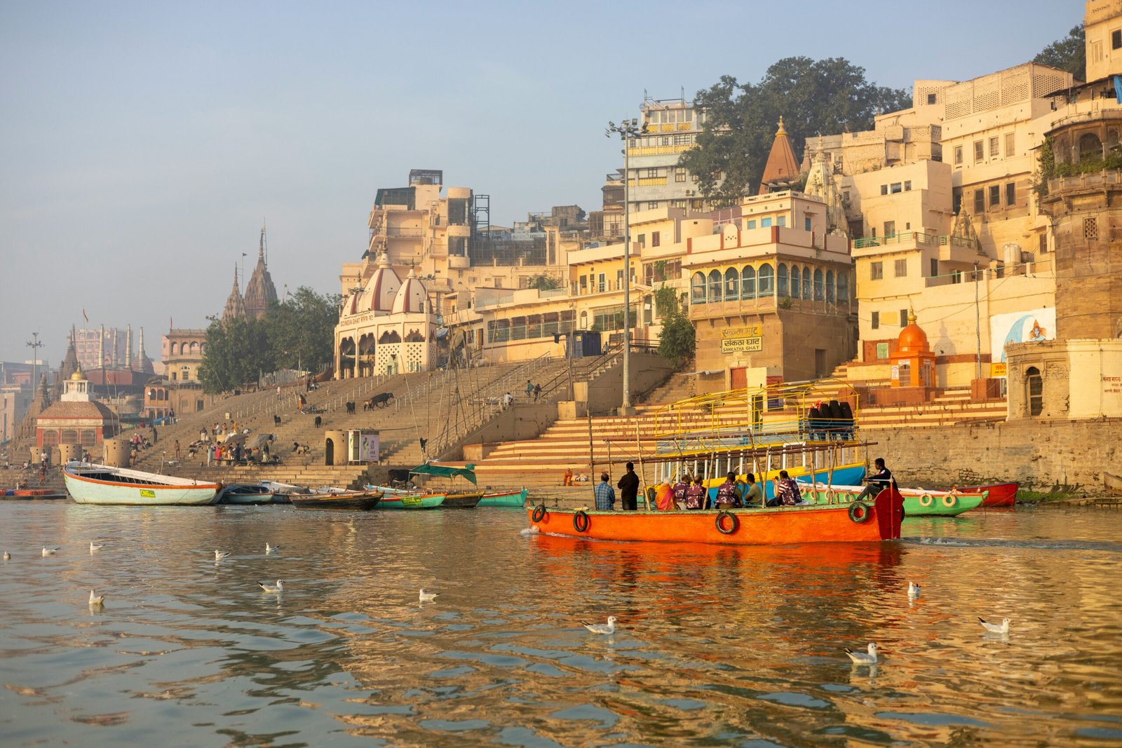 Colourful wooden boats moored along the ghats of Varanasi with the old city skyline behind