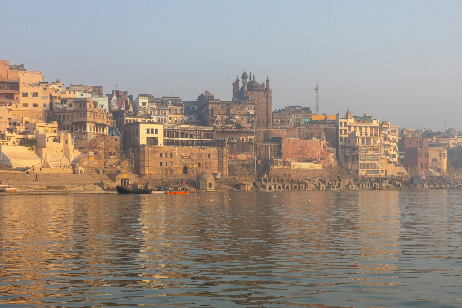 Calm view of the Ganga riverfront in Varanasi with the Alamgir Mosque minarets visible above the ghats