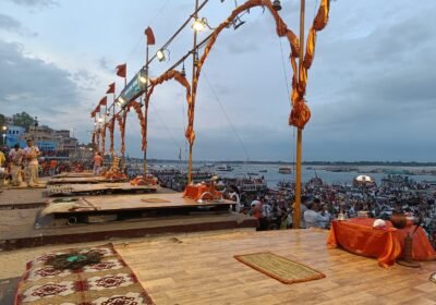 The Ganga Aarti platform on a Varanasi ghat at dusk, with boats and visitors along the river