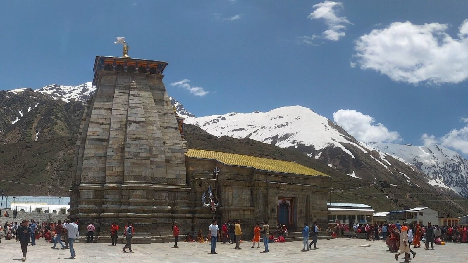 Kedarnath Temple with pilgrims in the courtyard and snow-capped peaks behind, Uttarakhand
